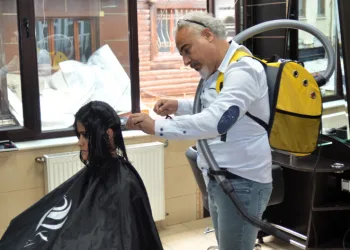 Elektrikli süpürge ile saç kesimi yapıyor