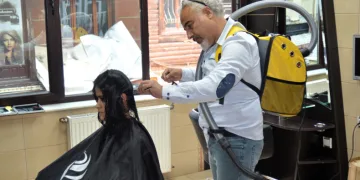 Elektrikli süpürge ile saç kesimi yapıyor