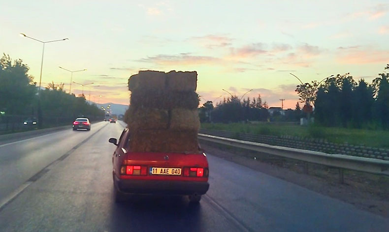 Trafikte otomobil üzerinde saman balyaları taşıdı