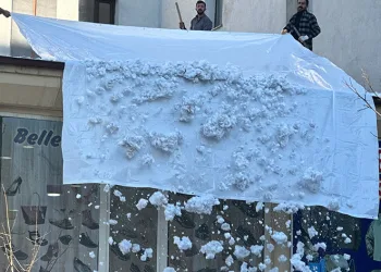 Vatandaşlar çatıdaki kar kütlelerini brandayla indirdi