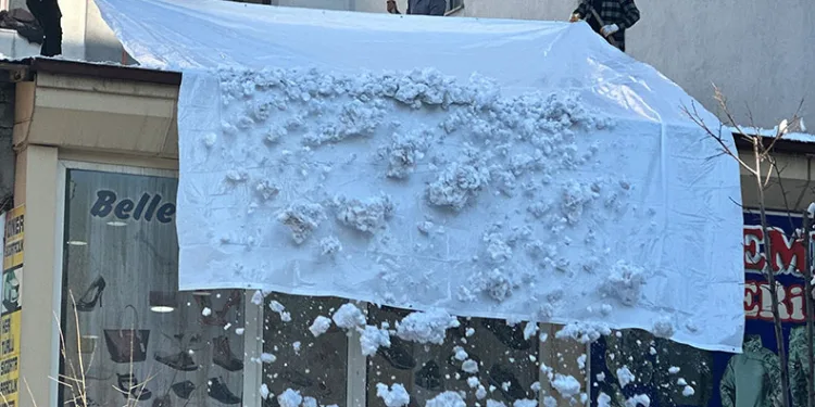 Vatandaşlar çatıdaki kar kütlelerini brandayla indirdi