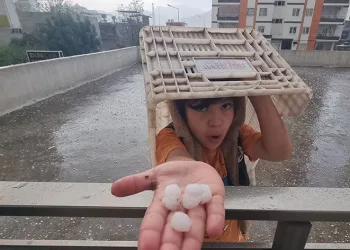 Dolu yağışında küçük çocuk plastik kasa altında eğlendi