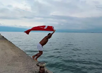 Soğuk ve yağışlı havaya aldırmadı, Türk bayrağıyla denize girdi
