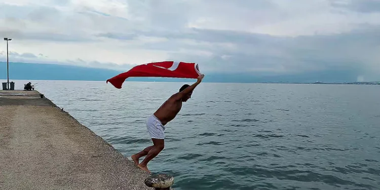 Soğuk ve yağışlı havaya aldırmadı, Türk bayrağıyla denize girdi